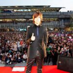 Performer posing on stage before large crowd