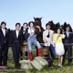 Seven people posing with horse in grassy field