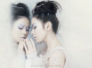 Woman with snowflake makeup touching frosted mirror