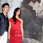 Actors posing in front of romantic movie poster