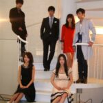 Six young adults posing on white spiral staircase