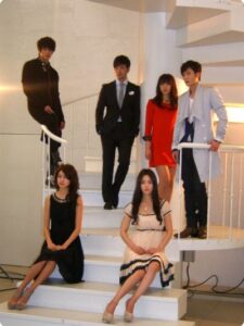 Six young adults posing on white spiral staircase