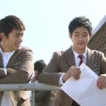 Two students in blazers leaning on railing