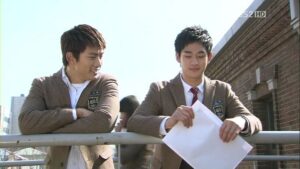 Two students in blazers leaning on railing