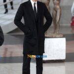 Man in black suit standing near sculpture