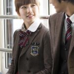 Two high school students in uniforms smiling
