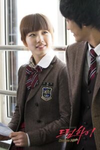 Two high school students in uniforms smiling