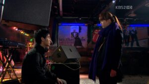 Man kneeling before woman in dim music venue