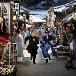 Two men running through snowy historical marketplace