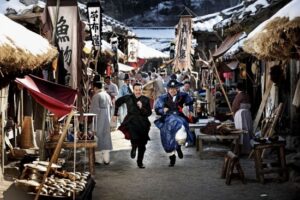 Two men running through snowy historical marketplace