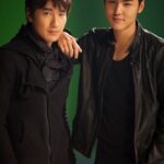 Two young men posing against green background