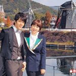Two people posing by windmills and canal