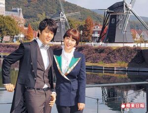 Two people posing by windmills and canal