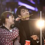 Couple sharing skewered street food at night