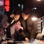 Two shoppers examining jewelry at night market stall