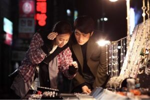 Two shoppers examining jewelry at night market stall