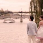 Couple holding hands by river with balloons