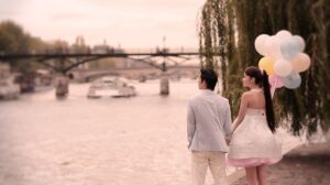 Couple holding hands by river with balloons