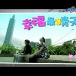 Two people sitting in park with city tower