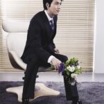 Man in suit sitting on chair holding bouquet