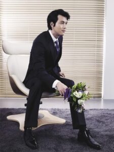 Man in suit sitting on chair holding bouquet