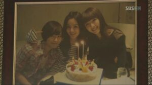 Three women smiling behind a birthday cake