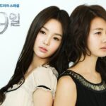 Two women posed back-to-back, gazing away