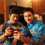 Two men in blue outfits clinking glasses