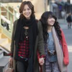 Two women walking on city street holding hands
