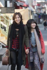 Two women walking on city street holding hands
