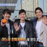 Three smiling men waving at camera