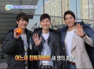 Three smiling men waving at camera