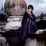 Woman in flowing dark gown on stone bridge