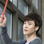 man cleaning window with white duster
