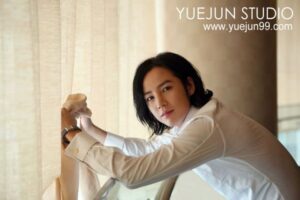 Person in white shirt adjusting curtain by window