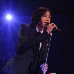 Singer in suit performing with microphone under spotlight