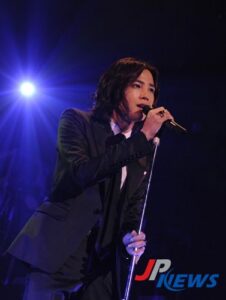 Singer in suit performing with microphone under spotlight