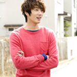 Smiling young man in pink sweater outdoors