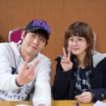 Two smiling people showing peace signs