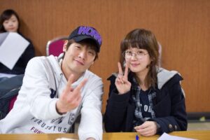 Two smiling people showing peace signs