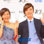 Two smiling people waving at event