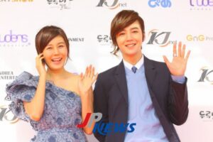 Two smiling people waving at event