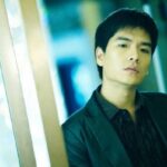 Young man leaning against glass wall