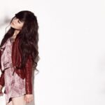 Woman in red leather jacket leaning against wall