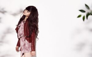 Woman in red leather jacket leaning against wall