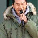 Smiling man in green parka speaking into microphone