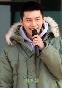 Smiling man in green parka speaking into microphone