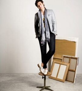 Man in blazer and scarf posing on stool