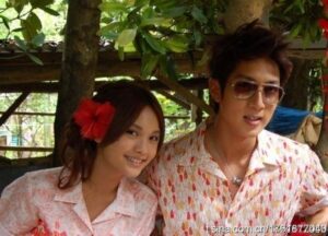 Smiling couple outdoors, woman with red flower