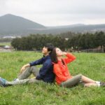 Couple sitting back to back in grassy field